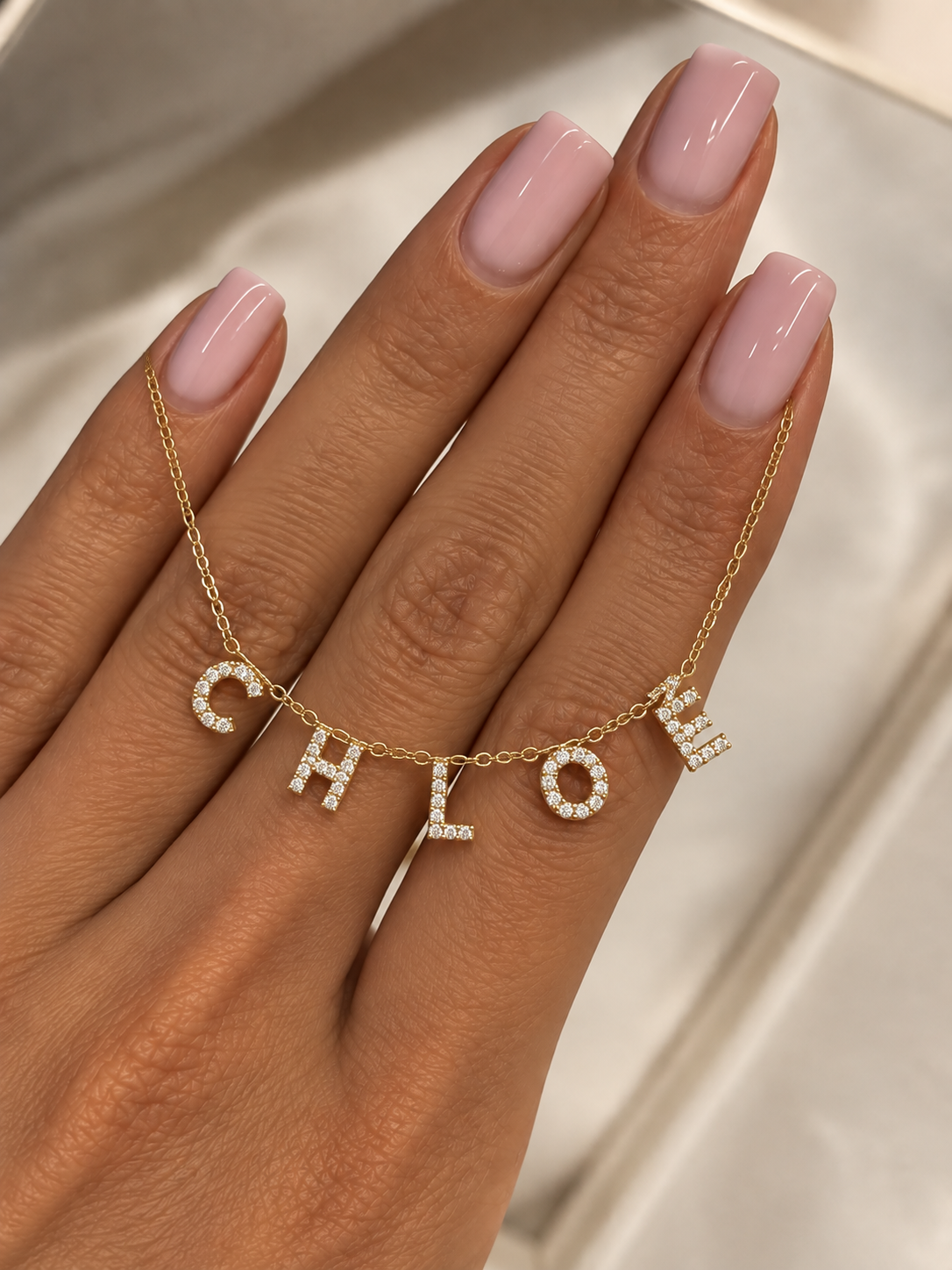 Collier à lettres personnalisé Dyna&co tenu délicatement en main